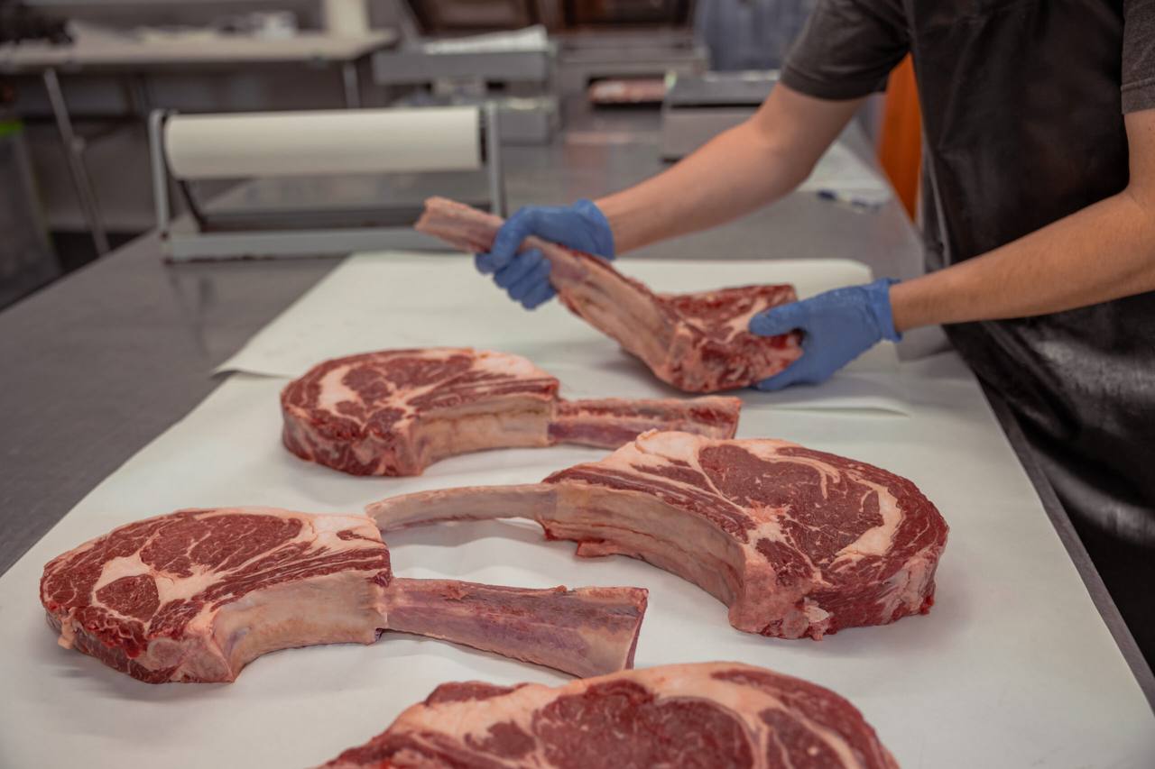 Butcher with Tomahawk ribeyes at Voiron's Abattoir